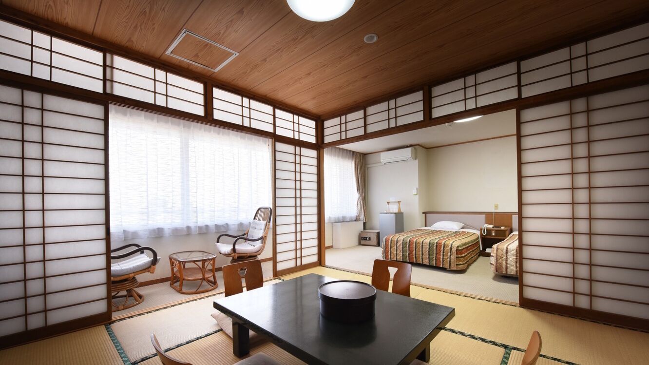 Una habitación tradicional japonesa con suelo de tatami, una mesa baja, una silla y una cama con futón.