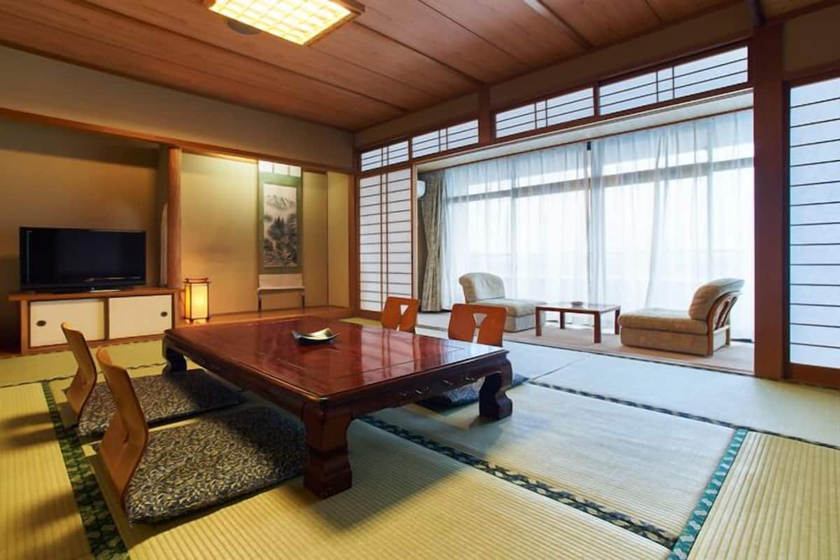 Perinteinen japanilaistyylinen huone, jossa on tatamimatto, matala puupöytä ja televisio.