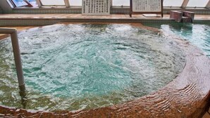 Un bain dans une source thermale, avec vue sur le ciel à travers de grandes fenêtres.