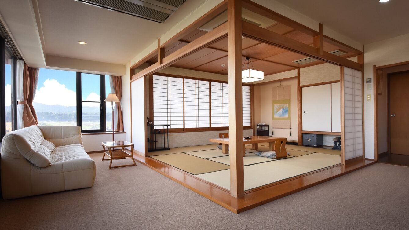 Una habitación tradicional japonesa con suelo de tatami, una mesa baja, un sofá y puertas correderas.