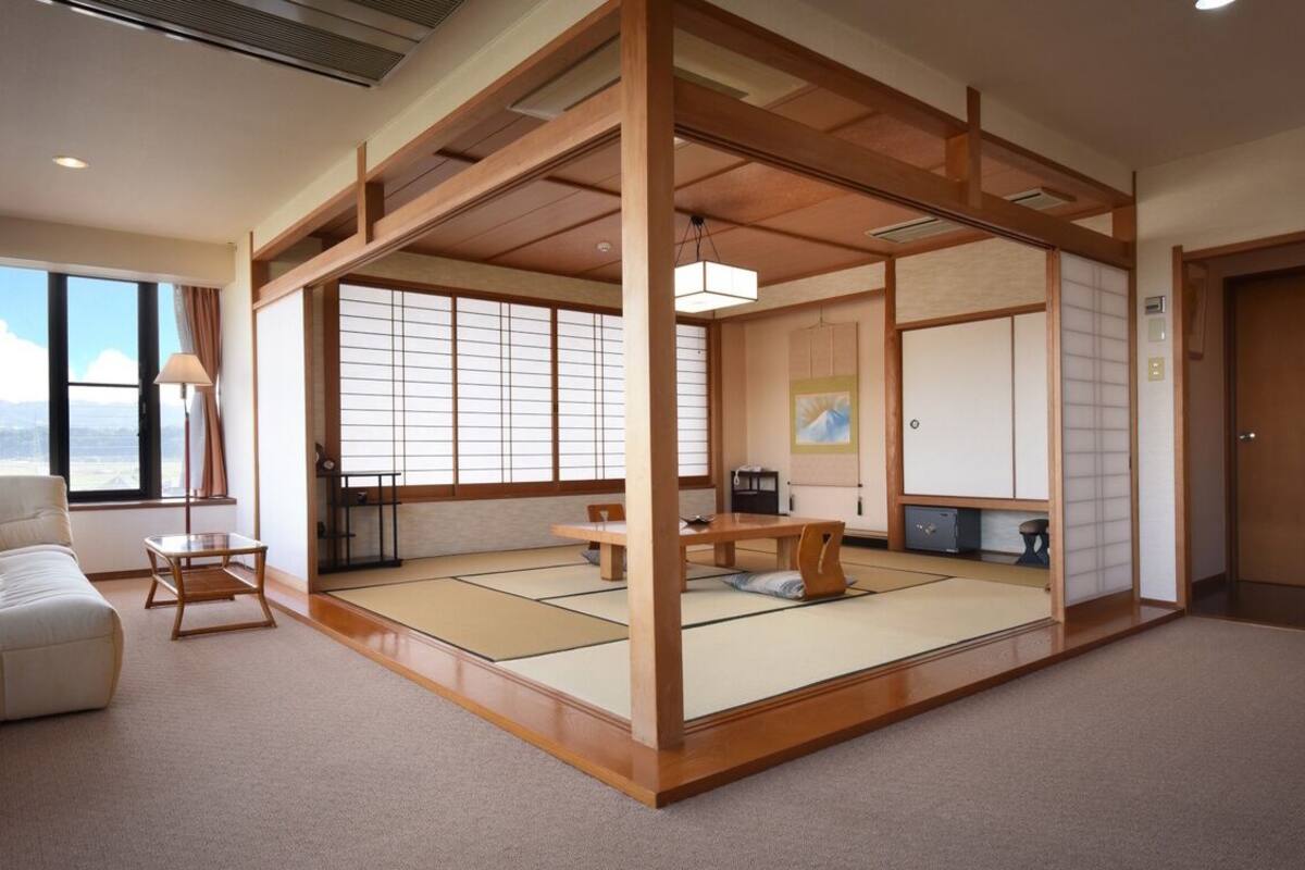 Perinteinen japanilaistyylinen huone, jossa on tatamimatto, matala pöytä, sohva ja liukuvat ovet.