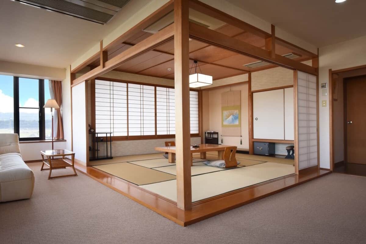Una habitación tradicional japonesa con suelo de tatami, una mesa baja, un sofá y puertas correderas.