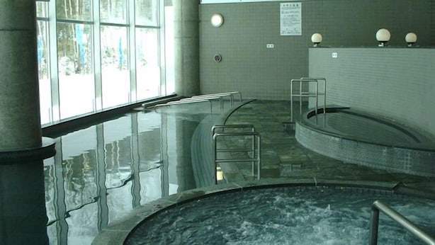 A spa area with a hot tub, glass walls, and a tiled floor.