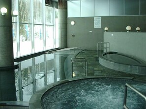 Ein Wellnessbereich mit Whirlpool, Glaswänden und gefliestem Boden.
