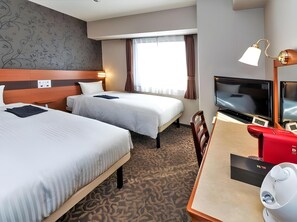 Ein Hotelzimmer mit zwei Betten, einem Fernseher, einem Schreibtisch mit Kaffeemaschine und einem gemusterten Teppich.
