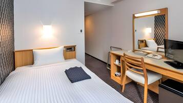 Quarto de hotel com cama, escrivaninha, cadeira e um espelho grande.