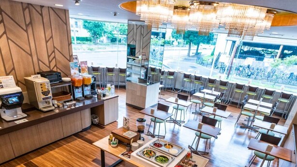 Um café moderno com piso de madeira, uma mesa central para servir comida e bebidas, e uma máquina de café.