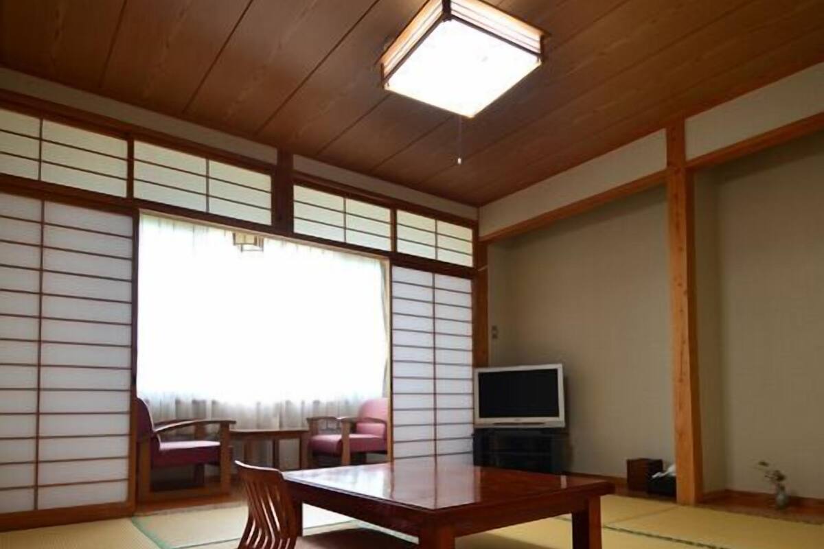 Una habitación japonesa tradicional con suelo de tatami, una mesa de madera baja y puertas correderas shoji.