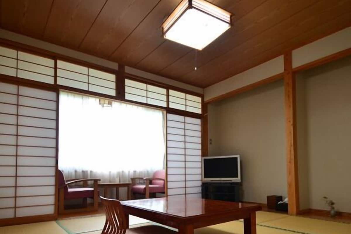 Una habitación japonesa tradicional con suelo de tatami, una mesa de madera baja y puertas correderas shoji.