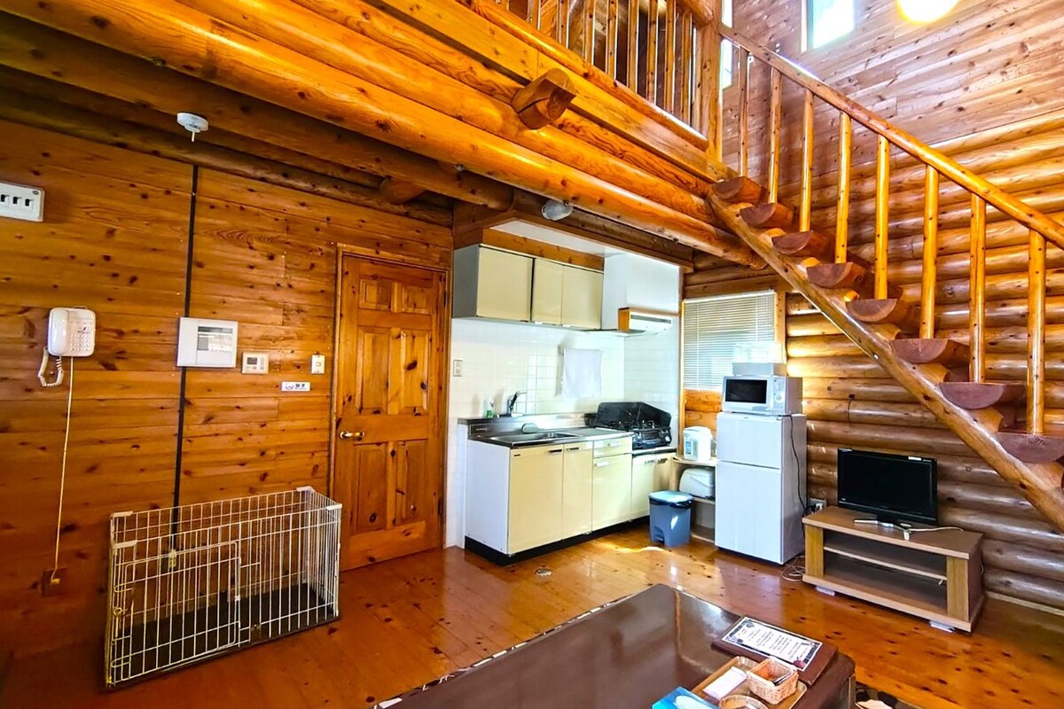 L’intérieur d’une cabane en rondins comprend une cuisine, un coin repas et un escalier.
