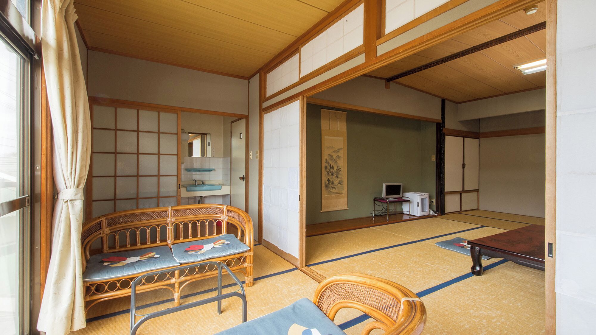 Perinteinen japanilainen huone, jossa on tatamimatto lattiana, matala puupöytä, sohva ja tatamimatosta tehty tuoli.