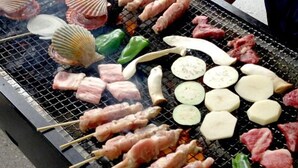 Verschiedene Fleisch- und Gemüsesorten werden auf einem Grill gegrillt.