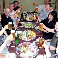 Un grupo de personas sentadas alrededor de una mesa con diversos platos y bebidas.