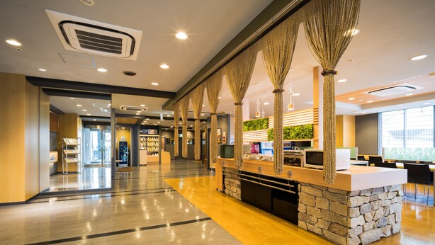 Un moderno vestíbulo de hotel con una recepción, una estación de café y un área de descanso.