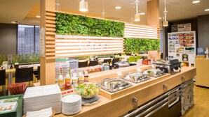 Un área de buffet con una variedad de alimentos, un bol de ensalada y un dispensador de bebidas.