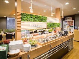 A buffet area with a variety of food items, a salad bowl, and a beverage dispenser.