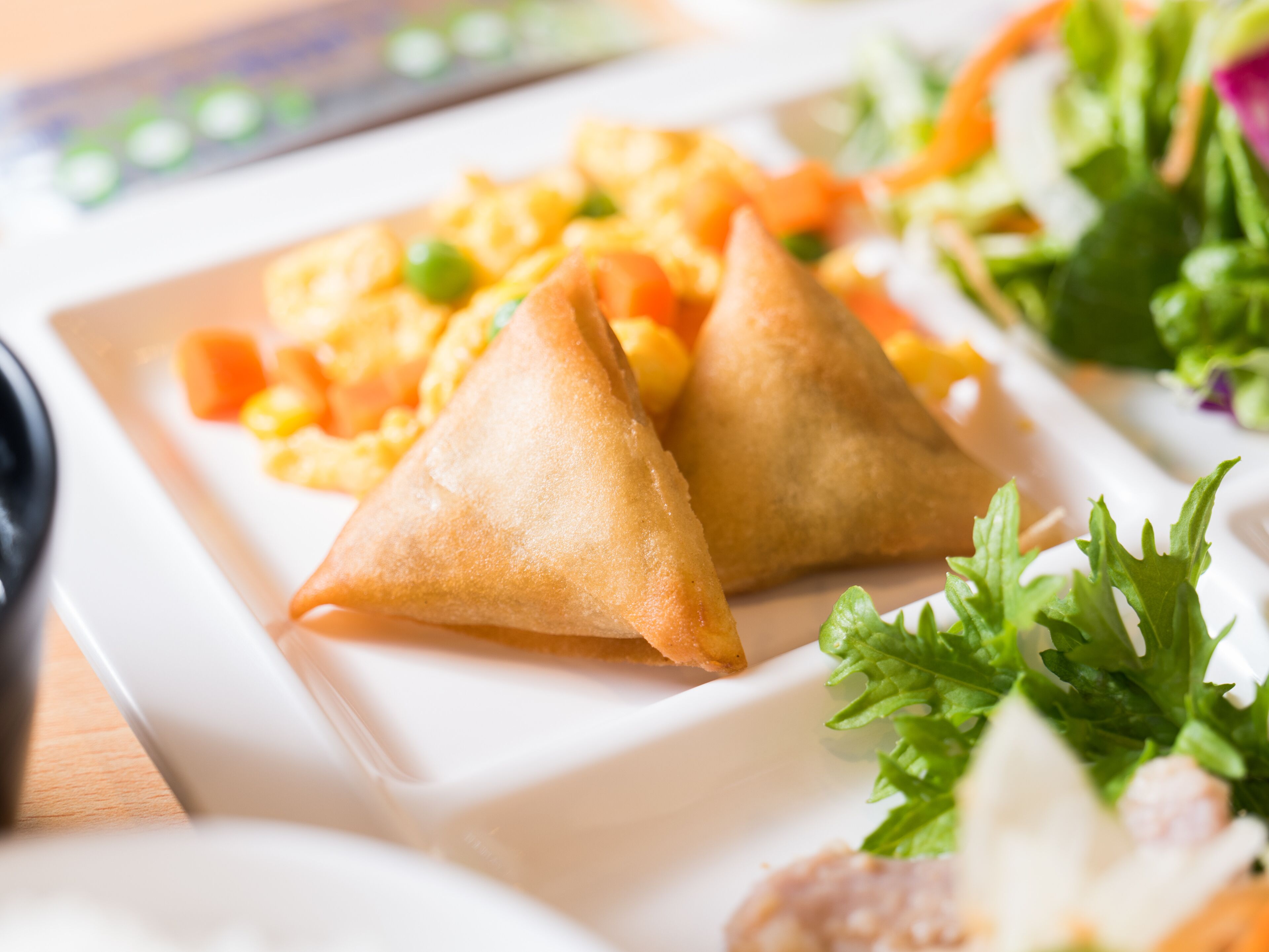 A plate with two samosas and a side salad.