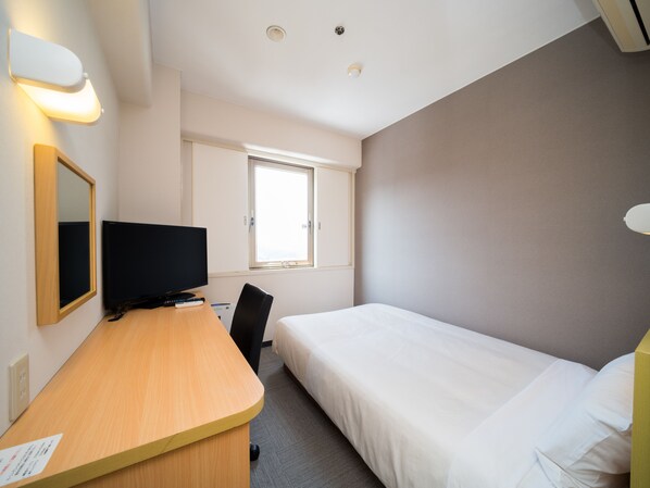 Una habitación de hotel con una cama, un escritorio con televisor, una silla y una ventana.