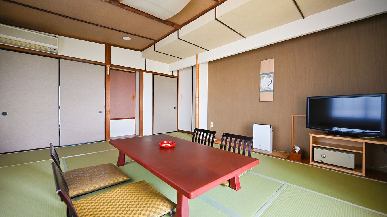 A traditional Japanese-style room with tatami flooring, a low wooden table, and a television on a wooden stand.
