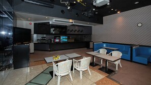 A restaurant with a counter, seating area, and a television screen. - Itoen Hotel Toi (Izu)