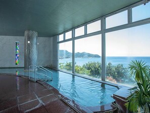 An indoor swimming pool with a view of the sea and mountains. - Itoen Hotel Toi (Izu)