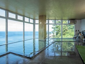 Ein großer, überdachter Pool mit Glasabdeckung, großen Fenstern und Blick auf den Ozean.
