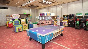 A room with arcade games, a ping pong table, and a variety of colorful gaming machines. - Itoen Hotel Toi (Izu)