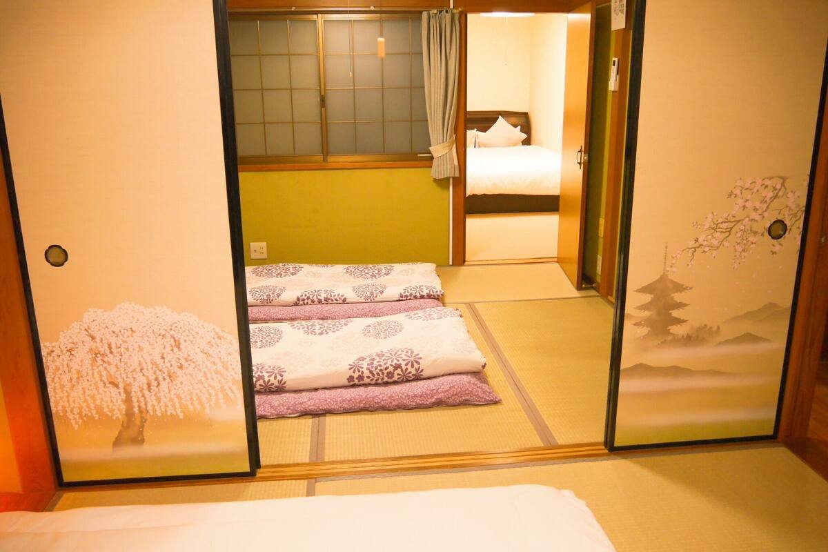 A traditional Japanese room with tatami flooring, a bed with white bedding, and a shoji screen door.