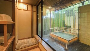 Uma onsen japonesa tradicional com um deck de madeira, uma nascente termal protegida por vidro e paredes de bambu.