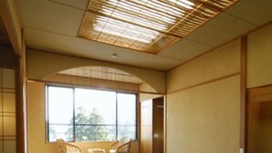 Um quarto japonês tradicional com tatames, uma mesa baixa e vista para o exterior.