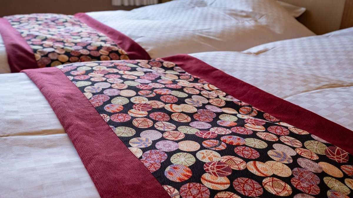 Ein Bett mit einem gemusterten Überwurf und Kissen.