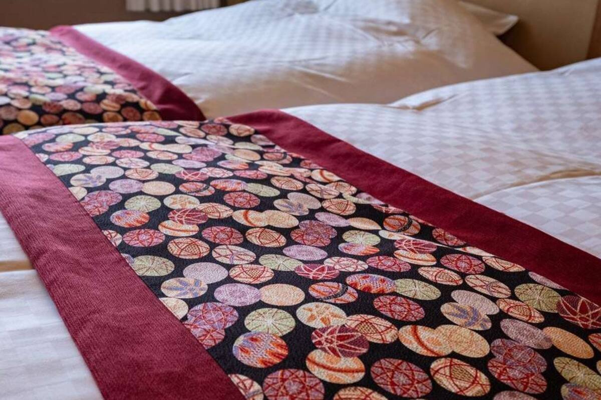 Ein Bett mit einem gemusterten Überwurf und Kissen.