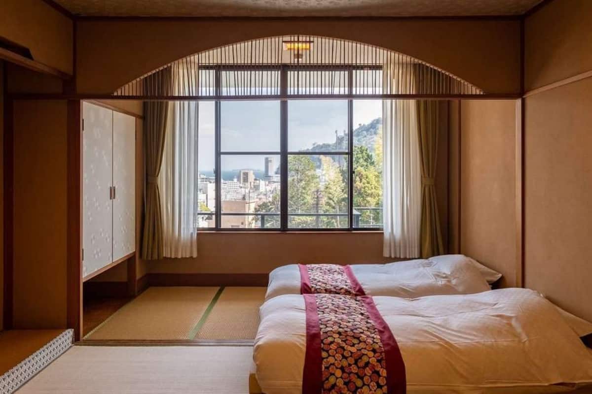 Et værelse med to senge, udsigt til bybillede og en traditionel japansk skydedør.