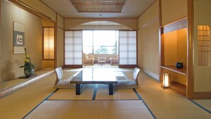 Um quarto japonês tradicional com tatames, uma mesa baixa e portas deslizantes.