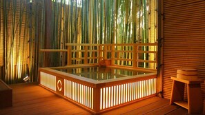 Un bain à remous doté d’une terrasse en bois et de murs en bambou.
