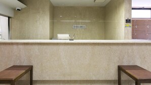 Ein Empfangstisch mit einem Schild für Greens Hotels, einer Überwachungskamera und einer hölzernen Sitzbank.