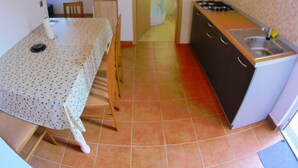 A compact kitchen with a dining area, wooden ceiling beams, and a tiled floor. - Apartments Anna Maria (Nin)