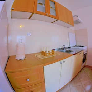 Una cocina compacta con armarios de madera, un fregadero y una estufa.
