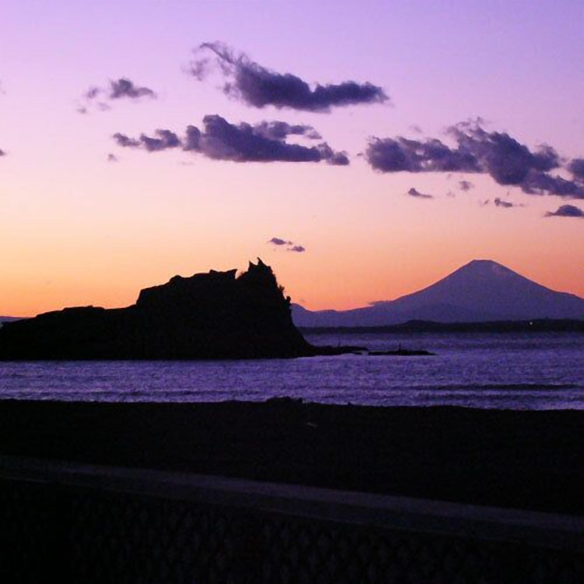 A coastal landscape with a prominent mountain silhouette during sunset.