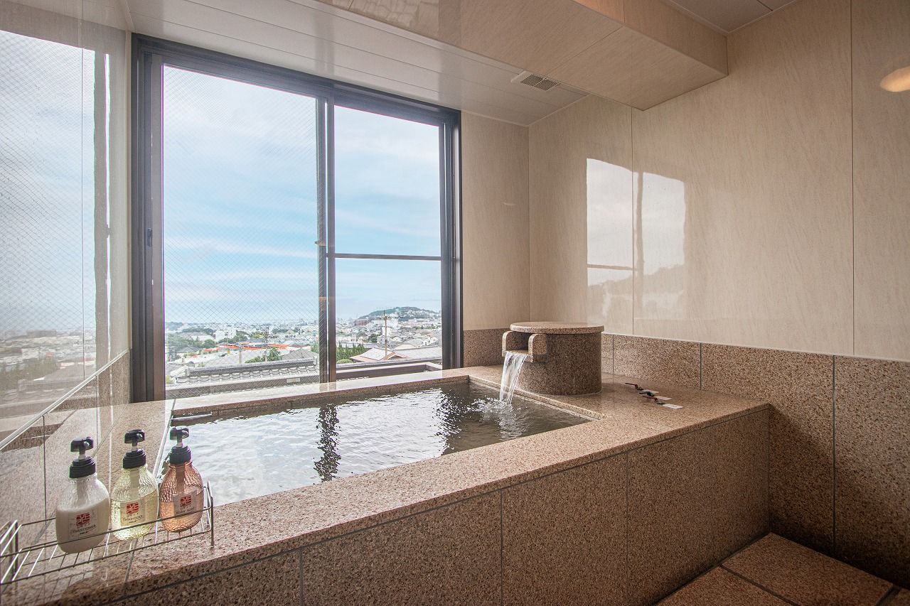 Un baño moderno con un ventanal amplio, una bañera integrada y una fuente de agua.