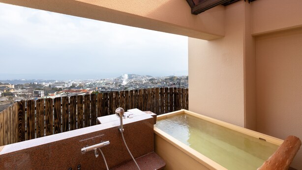 A balcony with a view of a cityscape, a wooden fence, and a small bathtub.