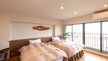 Habitación de hotel con dos camas, un ventanal grande y un equipo de aire acondicionado.
