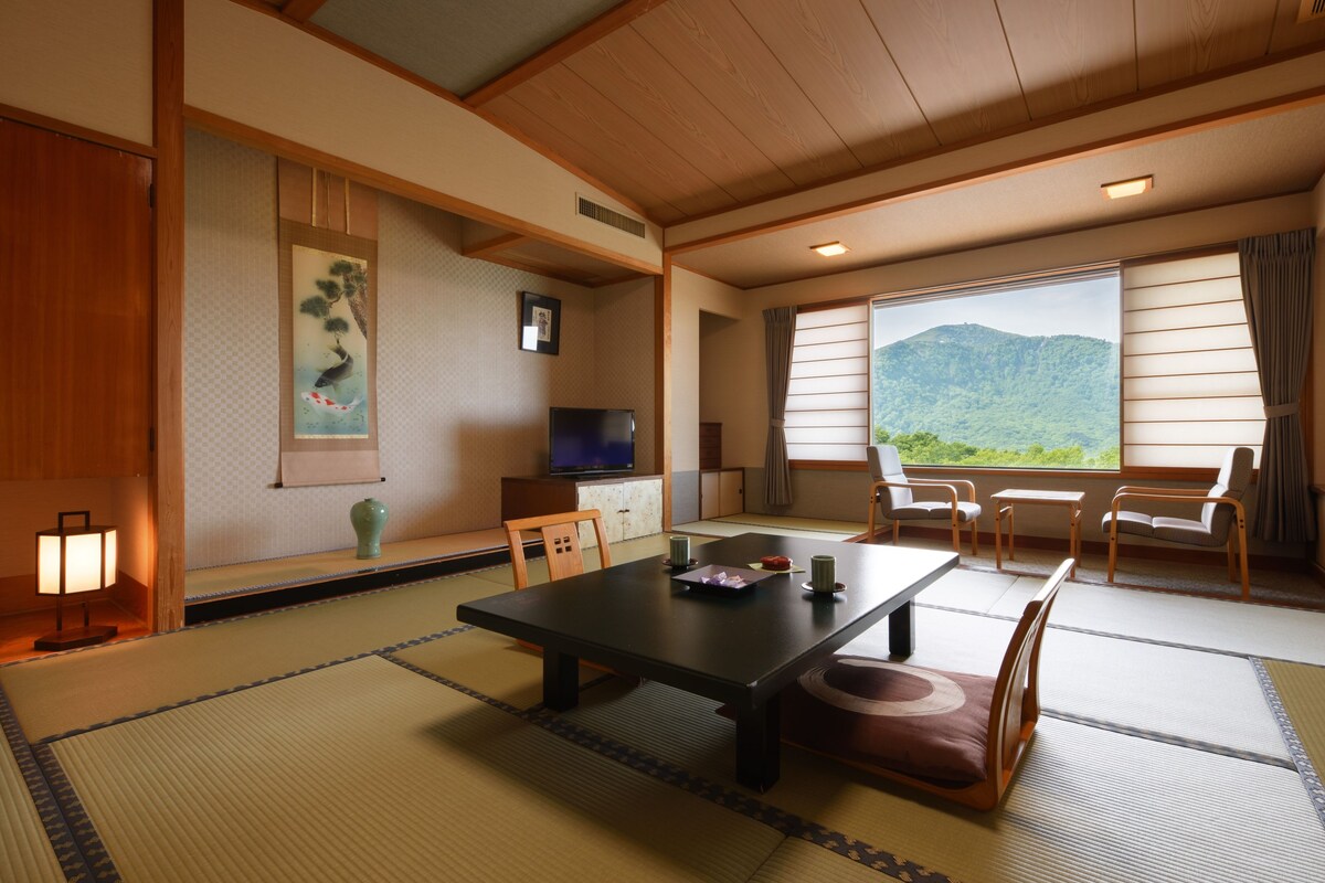 A traditional Japanese room with tatami flooring, a low table, and a television.