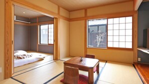 Una habitación tradicional japonesa con suelo de tatami, una mesa baja de madera y puertas correderas.