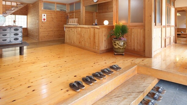 Un interior de madera con una mesa de recepción, un reloj y una planta.