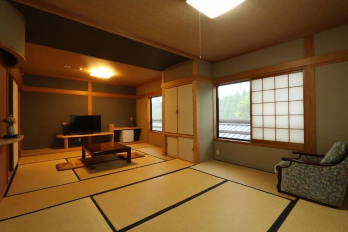 A traditional Japanese room with tatami flooring, a television, a sofa, and a sliding door.