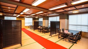 A conference room with tables and chairs, partitioned by sliding doors, and a red carpet.