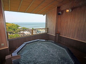 Un jacuzzi con terraza de madera y vista al océano.