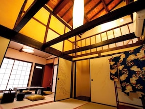 A traditional Japanese room with tatami flooring, a shoji screen, and a futon bed. - Takedamachiya Terakoya Hanatei (Asago)