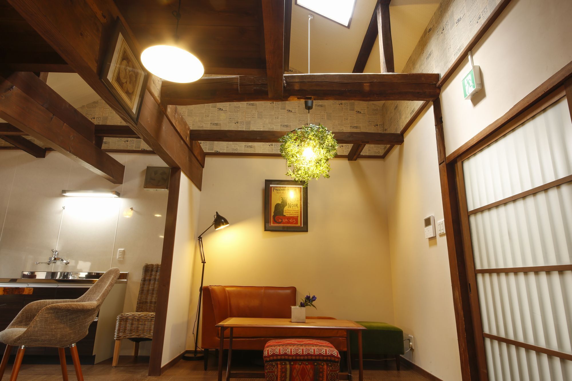 A cozy room with a wooden ceiling, a dining table, chairs, a bench, a hanging plant, and a framed picture.